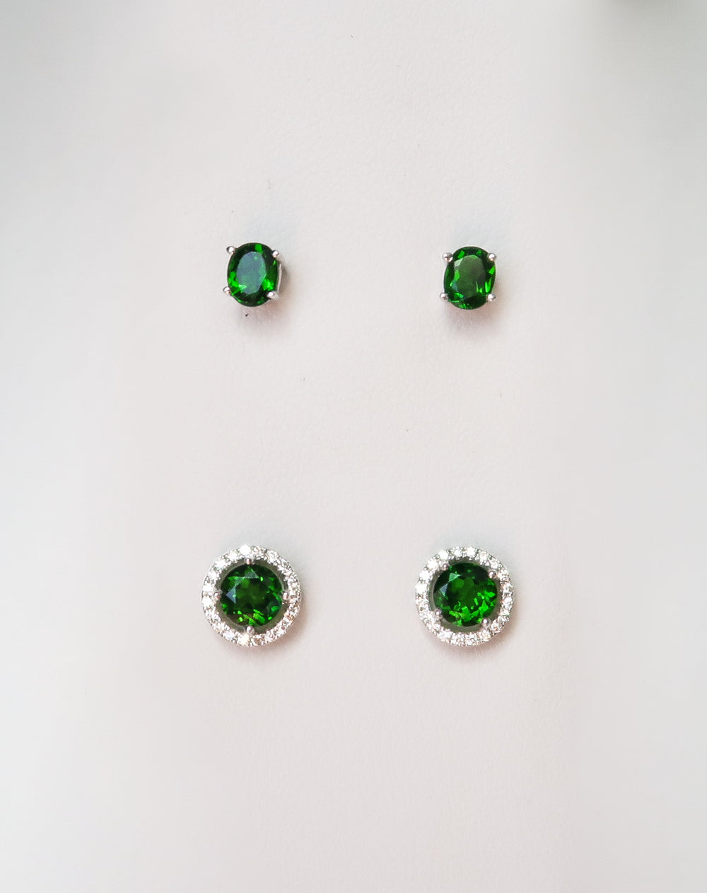 oval emerald stud earrings and round emerald with a diamond halo earring studs